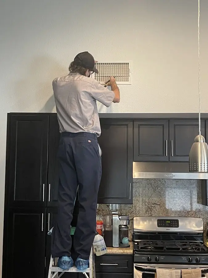 Technician inspecting an air vent during HVAC service in Joshua